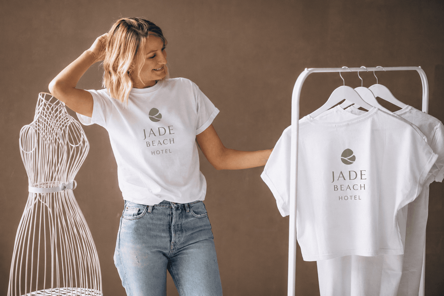 Woman modelling a Jade Beach Hotel branded t-shirt next to a rack of hotel-branded merchandise