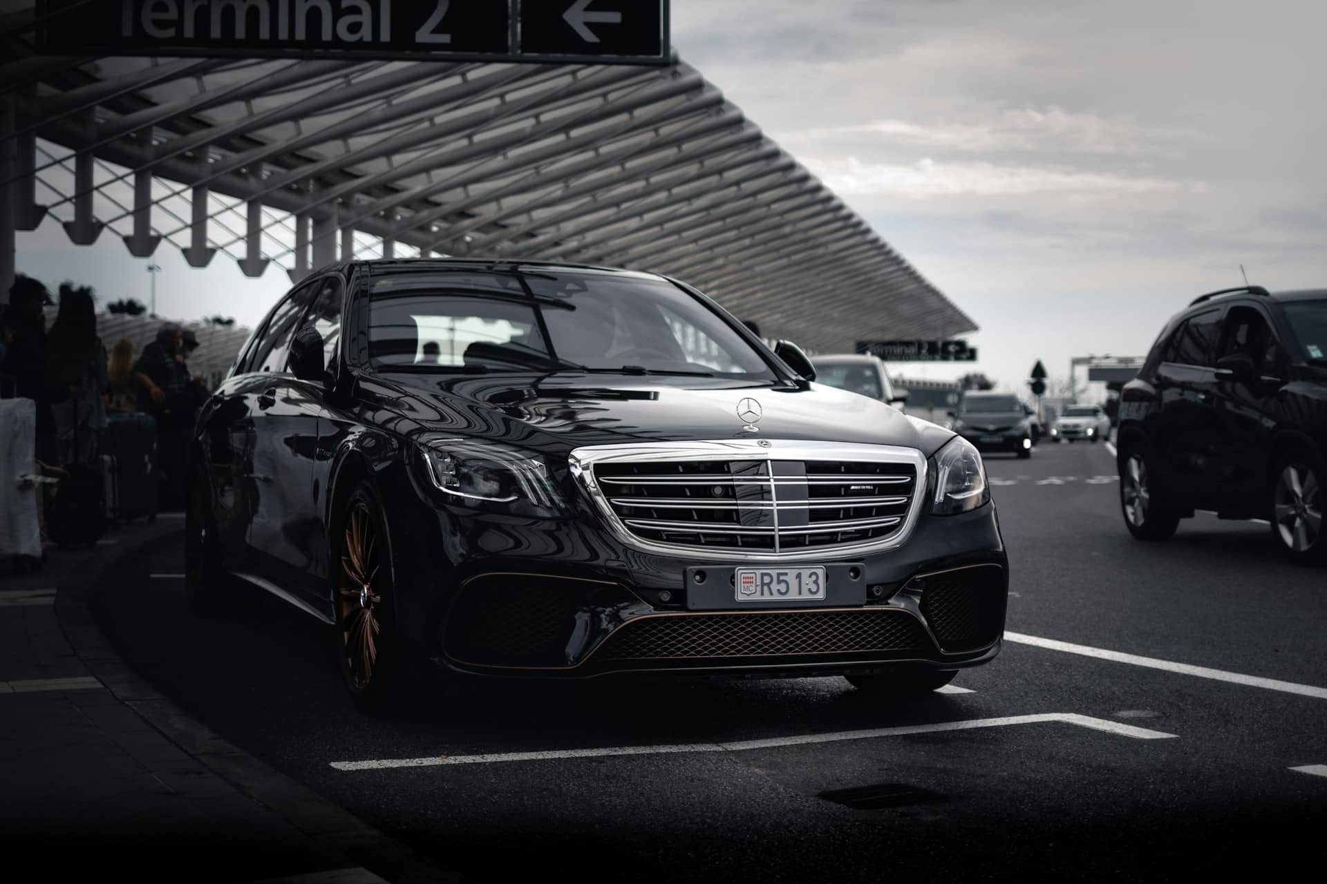 Black chauffeured Mercedes-Benz S-Class waiting outside an airport terminal
