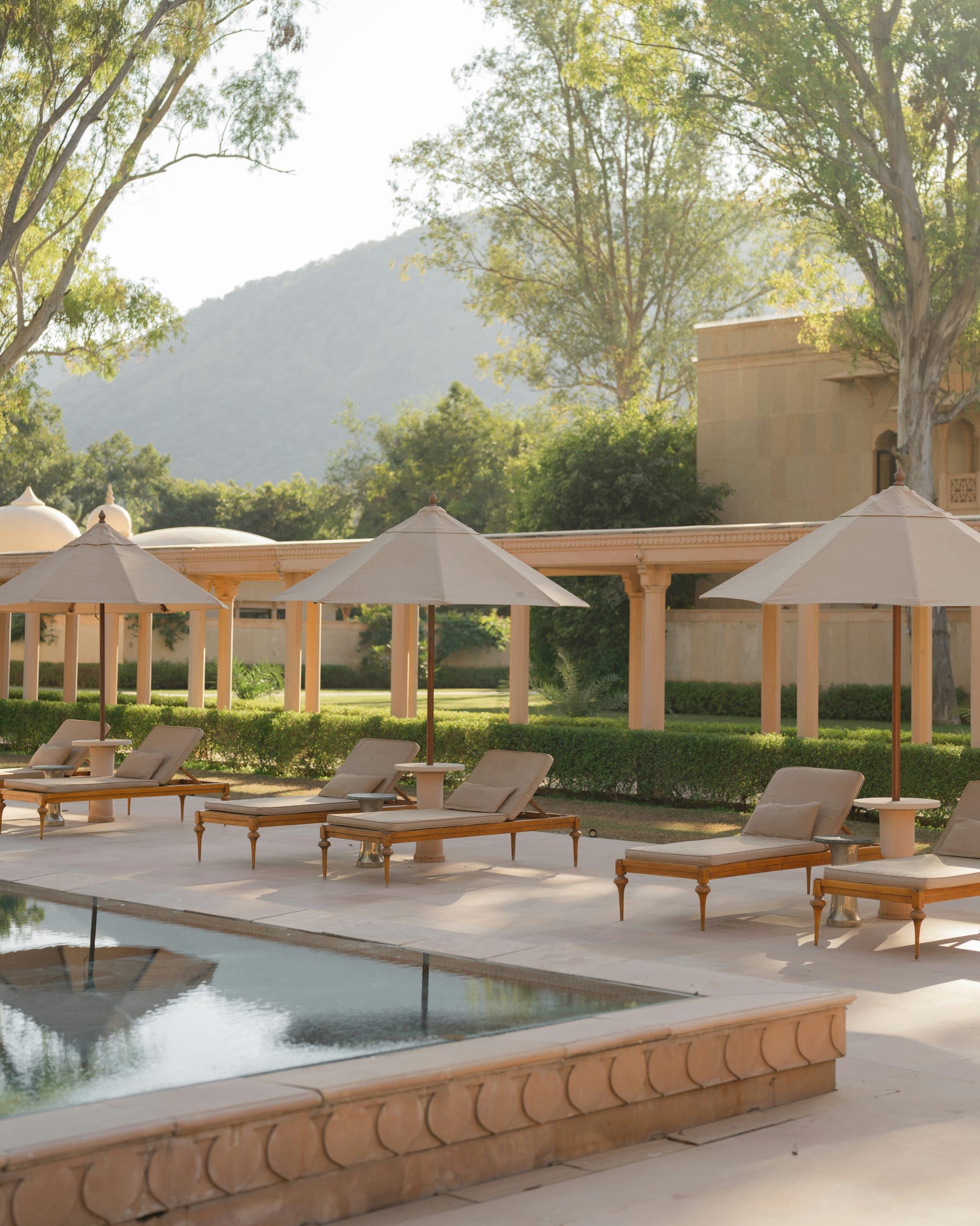 Row of poolside sunbeds under canopy umbrellas