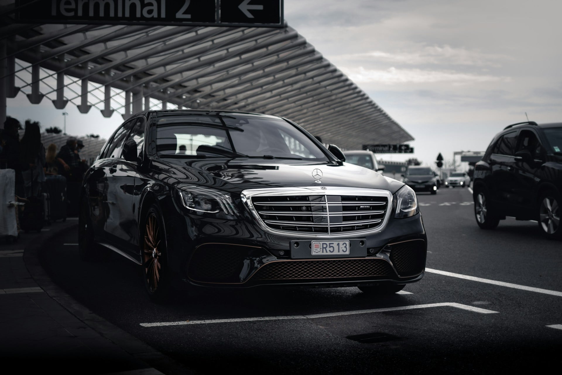 Mercedes-Benz S-Class nera con autista che attende davanti a un terminal aeroportuale