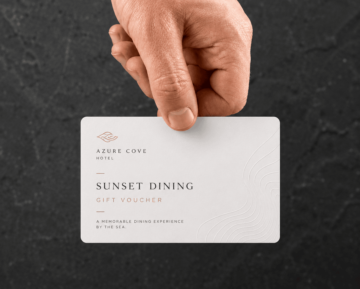 Hand holding a Sunset Dining gift voucher against dark stone